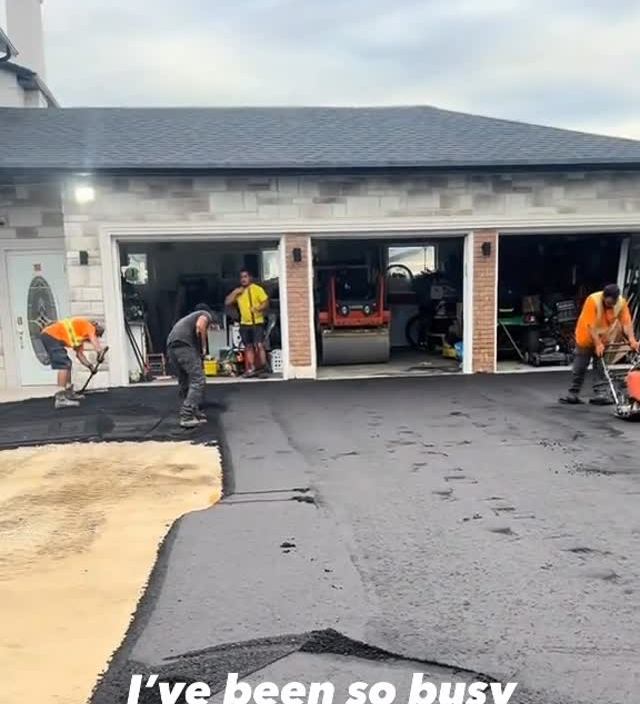Crew paving a wide driveway in front of a garage