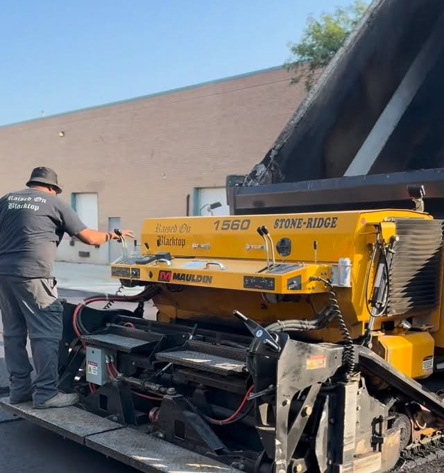 Yellow paving machine laying fresh asphalt
