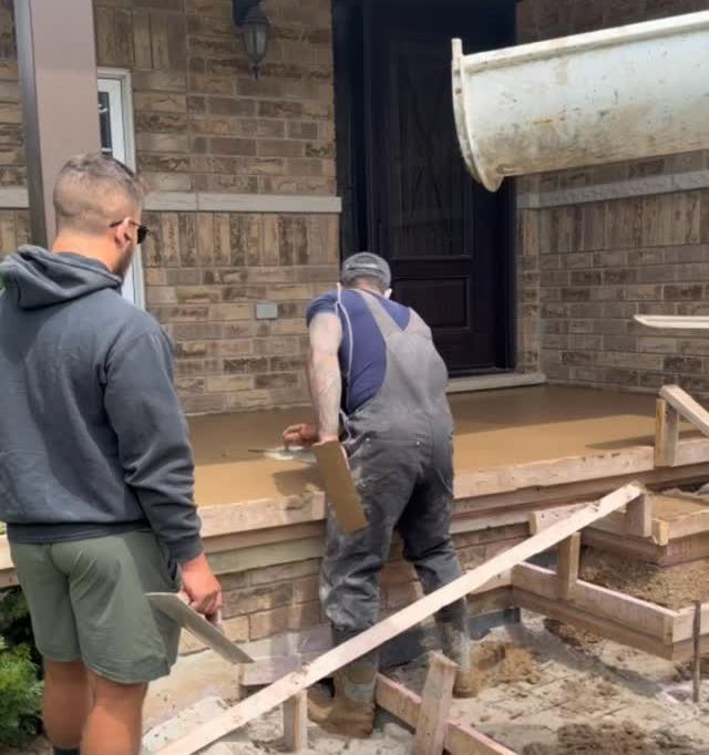 Two workers building forms for concrete steps at a front porch